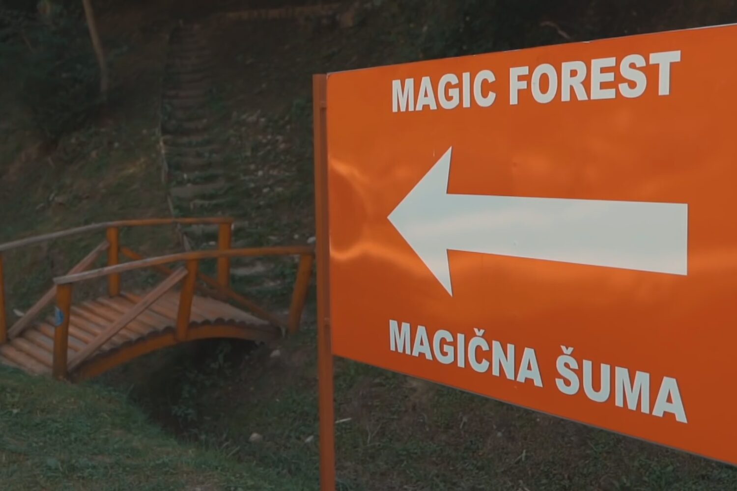 Sign pointing towards the "Magic Forest" near a small wooden bridge at the Bosnian Pyramid complex.