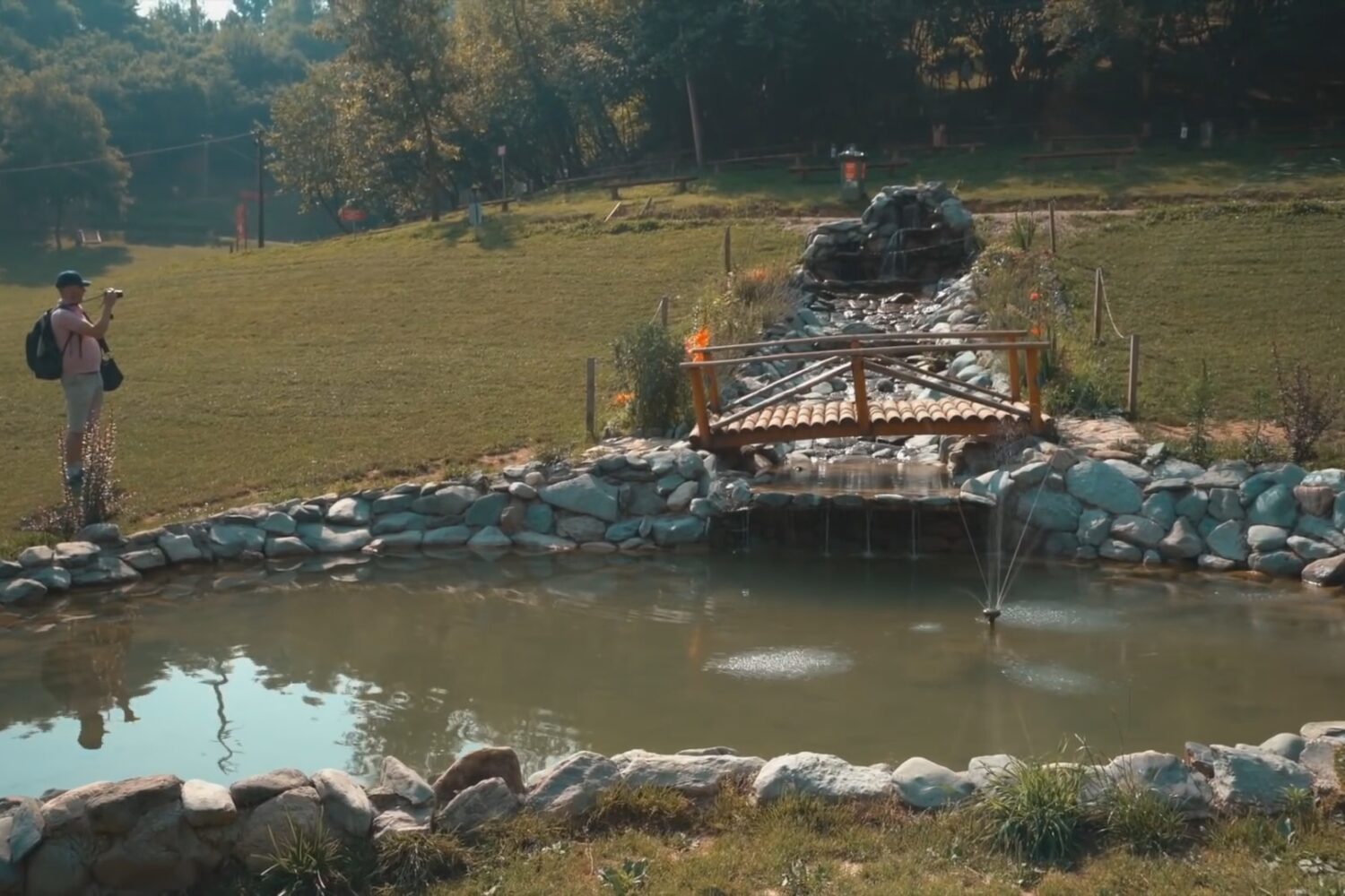 Scenic view of a small wooden bridge over a pond with cascading water at the Bosnian Pyramid complex.