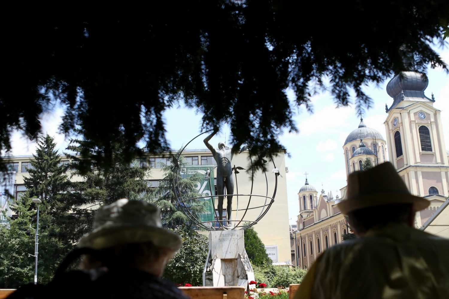 Multicultural Man statue in Sarajevo's Liberation Square Park with the Orthodox Church in the background