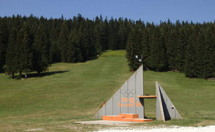 Concrete Olympic monument surrounded by green forest on Igman Mountain.