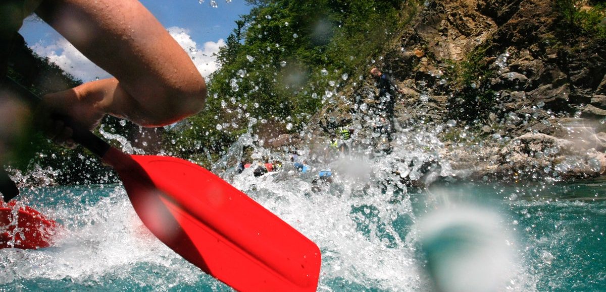 Close-up view of an oar splashing water during a white-water rafting adventure on the Neretva River.