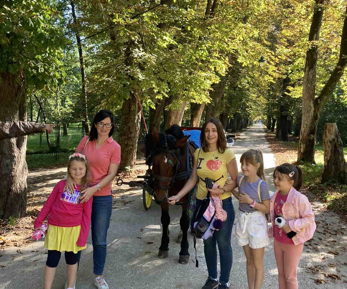 Children petting a horse at Vrelo Bosne with lush green surroundings.