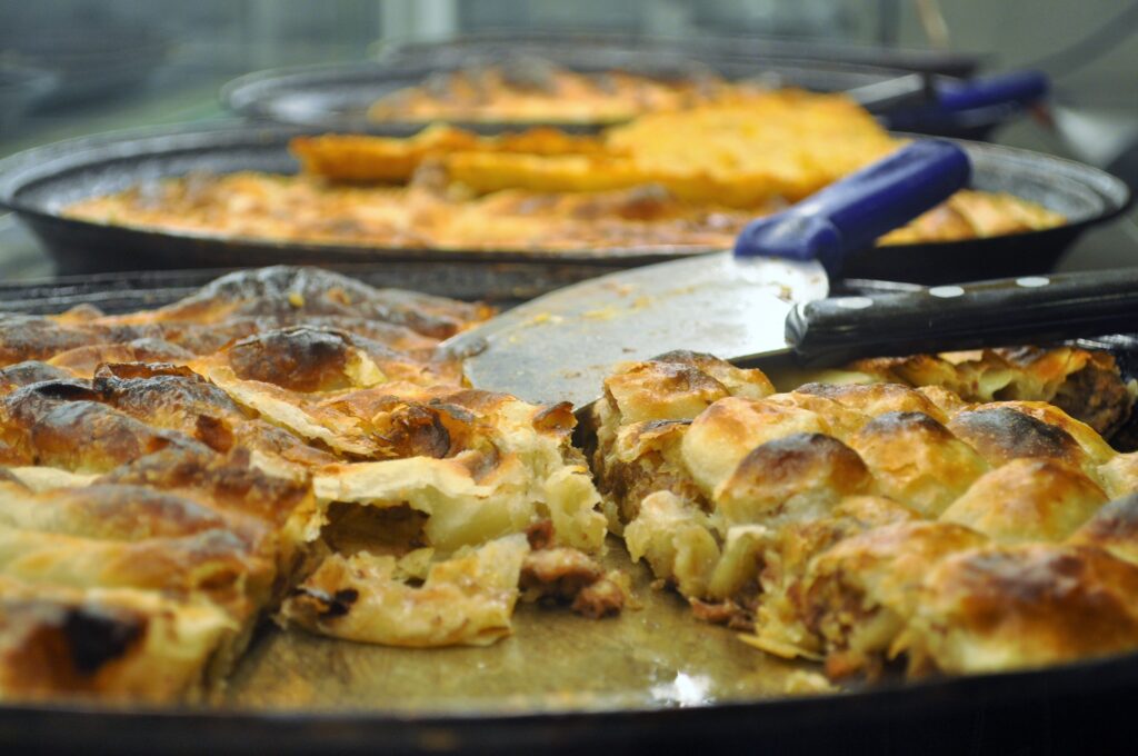 Freshly baked Bosnian burek in large trays, sliced and ready to be served in a traditional buregdžinica.