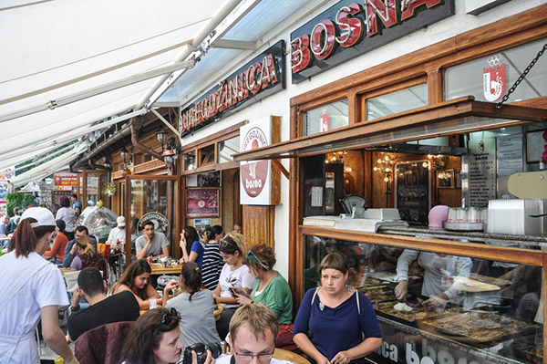 Outdoor seating at Buregdžinica Bosna, a popular eatery in Sarajevo, with people enjoying traditional Bosnian burek.